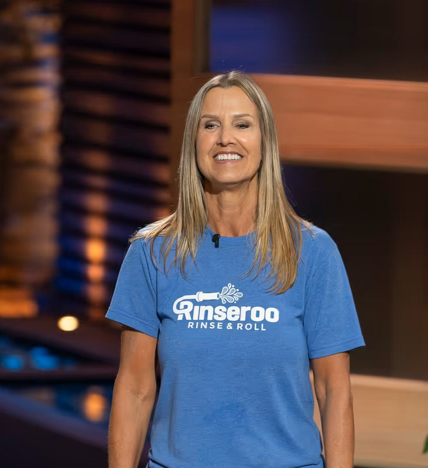 Rinseroo founder, Lisa wearing a blue 'Rinseroo Rinse & Roll' t-shirt against a blurred indoor background